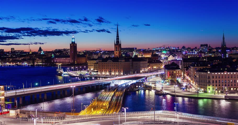 Nighttime cityscape of Stockholm, Sweden, with illuminated streets, bridges, and buildings reflecting on the water.