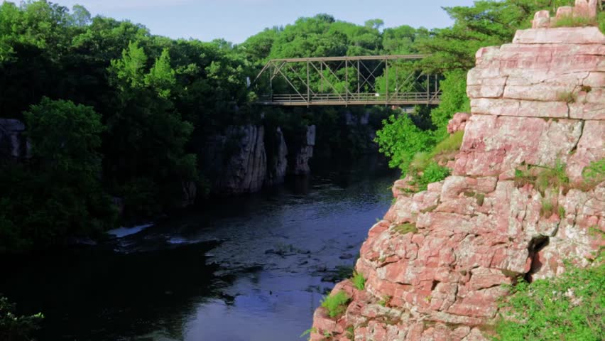 A bridge over the beautiful landscape of Palisades State Park in South Dakota. Rocky Cliffs covered in trees run along the river in this beautiful nature scene.