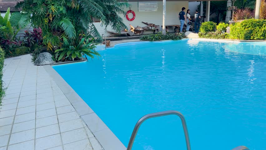 Wide shot of a bright blue swimming pool at a tropical resort in Thailand
