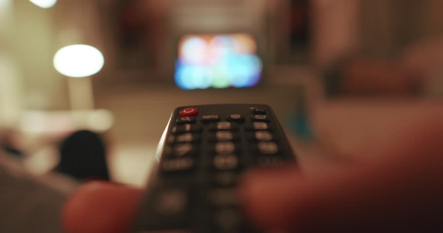 Remote control in hand pointing at a TV, indicating leisure time