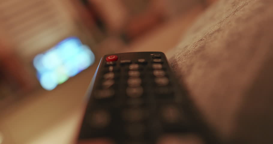 Hand holding remote, turning TV off, cozy indoor setting