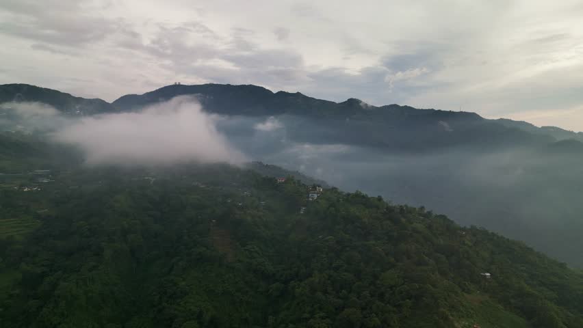 Picturesque aerial orbit of quaint mountaintop village covered in fog clouds during dusk - Benguet Province, Philippines