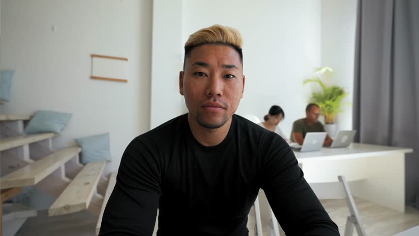 A man sits in front of a screen talking to a friend online. He shows signs of boredom while trying to engage in conversation during the chat.