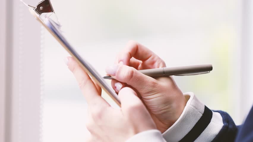 hand with pen writing on document