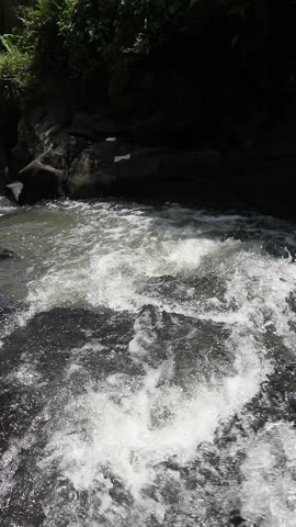 Powerful Rushing River Stream Over Rocks 

A high-angle close-up capturing dynamic white water rapids as a river surges forcefully over dark, rugged rocks in a natural outdoor environment.