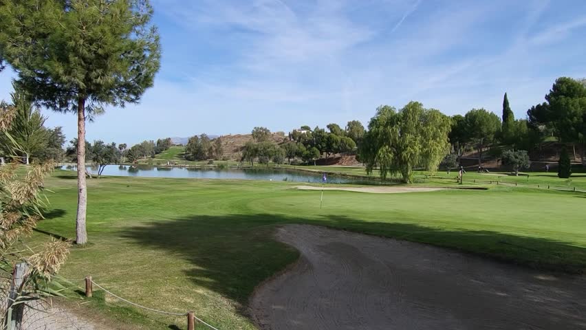 Golf course. Green, bunker, lake, and golfers on a sunny day. Panoramic view of a golf course. Spanish golf course. Spain.