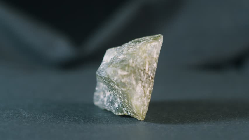 Piece of raw green tourmaline on black background rotating view