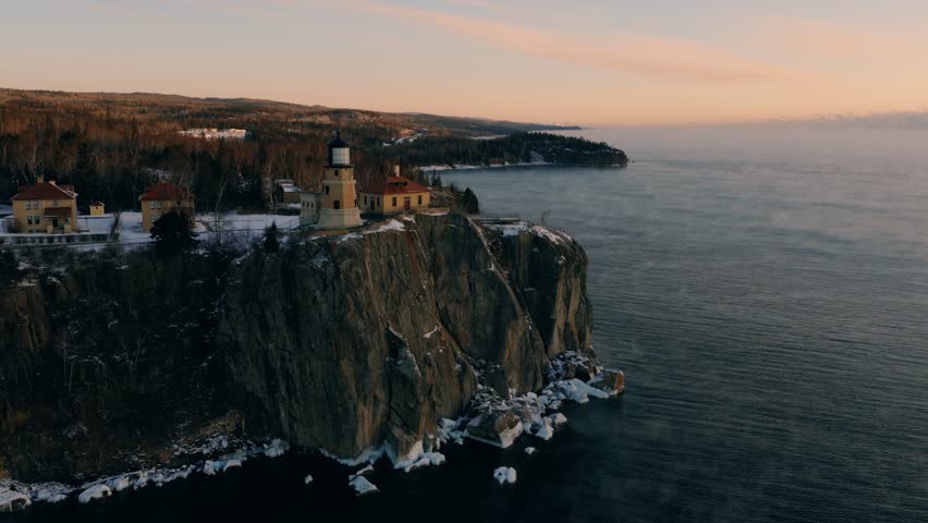 Detailed aerial shot of Split Rock Lighthouse on its cliff with the sun illuminating the North Shore forest behind it.
