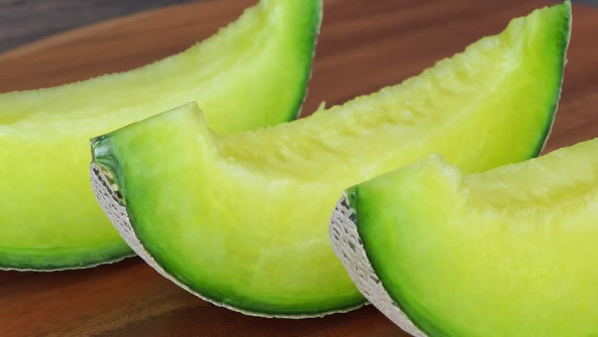 close up of a cantaloupe slice on a piece of wooden.