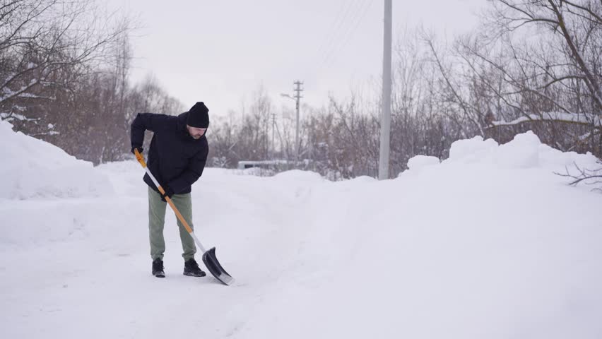 A man removes snow with a shovel on the road