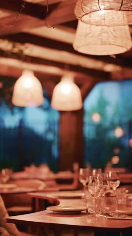 Evening dinner table setting in rustic restaurant with wicker lamp and warm lighting bokeh