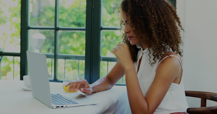 Woman typing laptop remote work, pink avatar causing overlay shifting to glass while sipping juice. Computer, beverage, window, daylight, workspace, productivity, minimalist