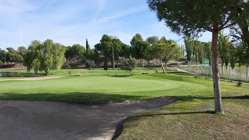 Golf course. Green, bunker, lake, and golfers on a sunny day. Panoramic view of a golf course. Spain.