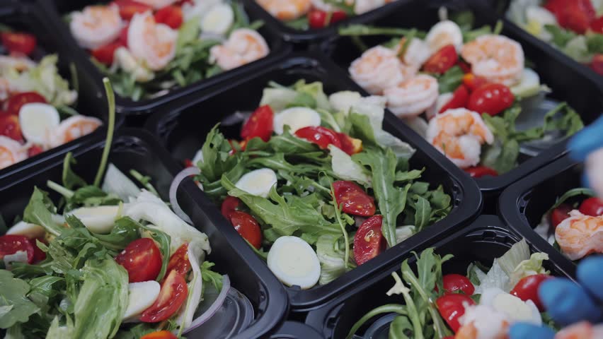 Fresh shrimp salad meal prep in black containers.
