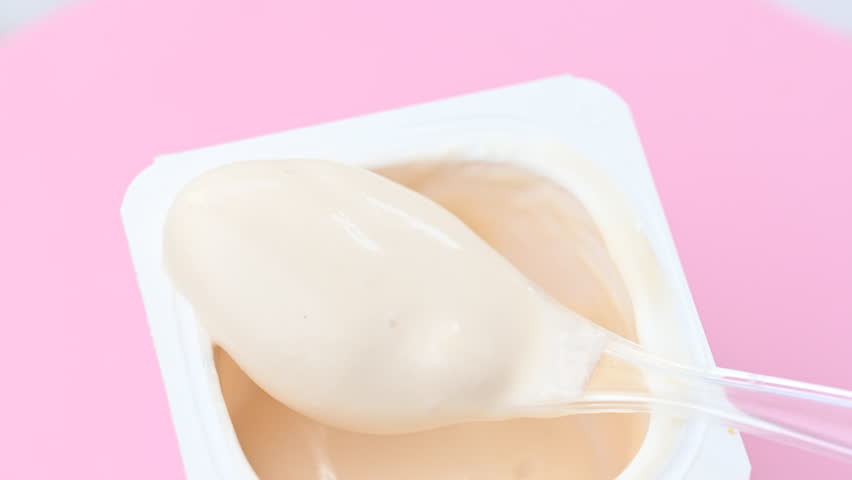 Video of yogurt with a spoon on a pink background
