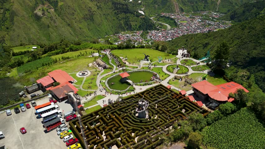 Cinematic aerial drone flight over the intricate Laberinto del Dragon hedge maze at Runtun ridge revealing geometric garden designs and tourists in the mountains of Banos Ecuador