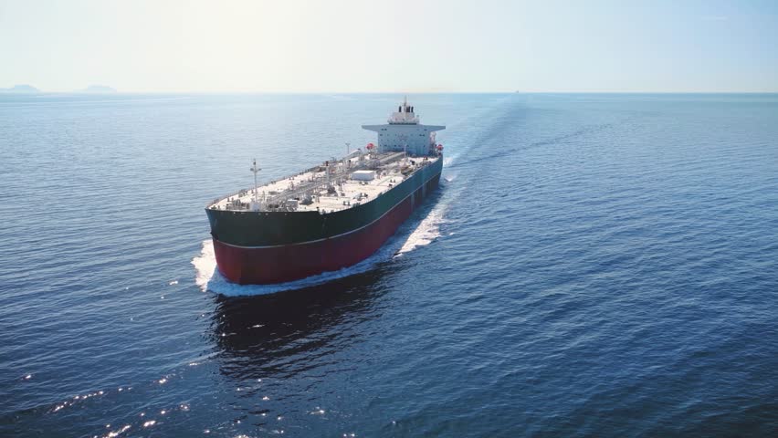 Aerial view of a crude oil super tanker ship traveling with speed over the calm ocean