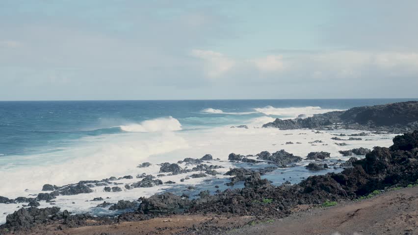Powerful ocean waves crashing on volcanic rocky shore