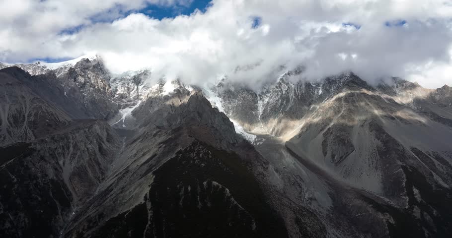 Aerial footage of beautiful high altitude snow capped mountains in the fog landscape