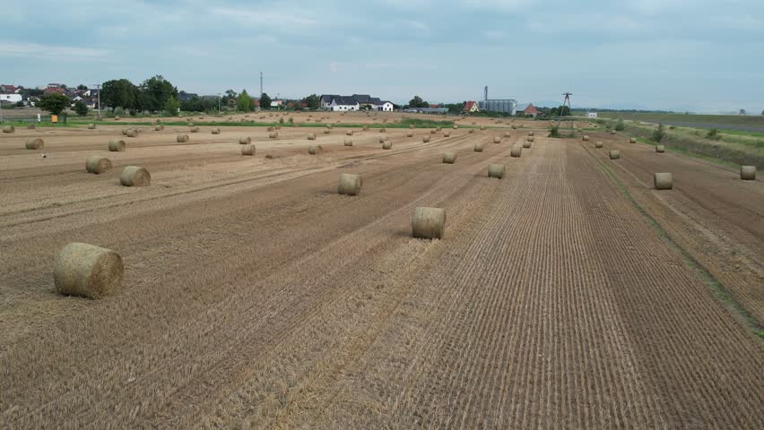 Drone flying over a harvested field with hay bales