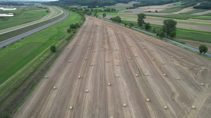 Aerial flying over a harvested field with round hay bales