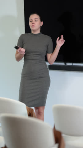 Young woman coach gives presentation using remote control in lecture hall