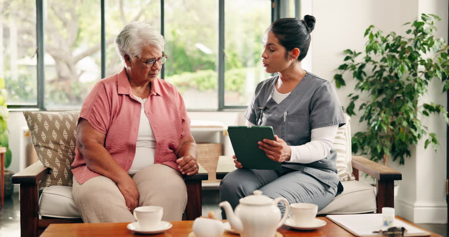 Old woman, nurse and bad news with tablet in home for healthcare report, explain or diagnosis on couch. People, caregiver and senior patient on sofa with app, consulting and support in retirement