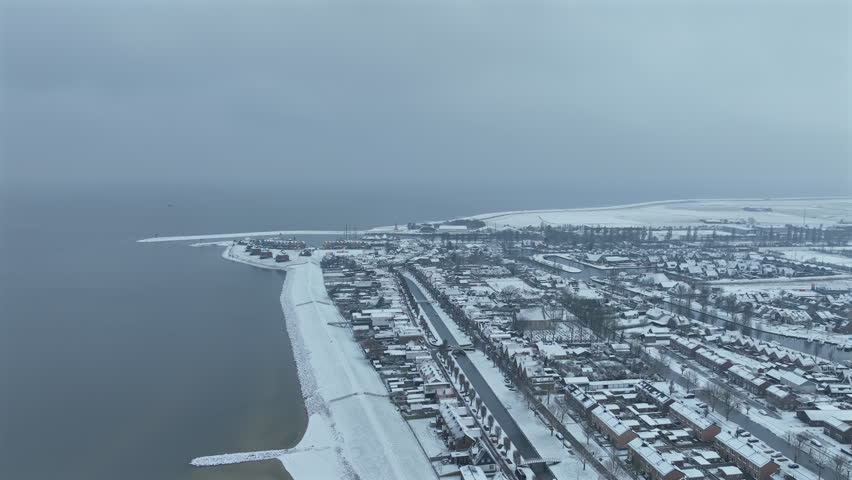 Overview of a snowy historic european city with traditional buildings, rooftops and waterfront in a coastal urban setting in winter