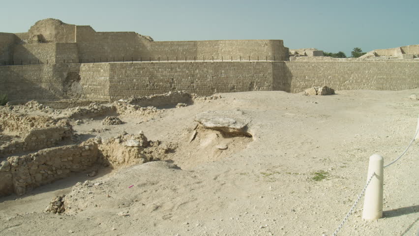 The clip showcases the historic Bahrain Fort with its stone walls and ruins set against a desert landscape. The fort features a flag atop its structure, highlighting its significance.