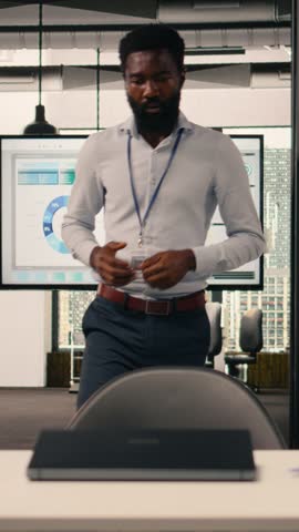 Vertical Video African american man, working with laptop, modern office, visual data, KPI metrics, business intelligence, planning for development, performance review, research and development.