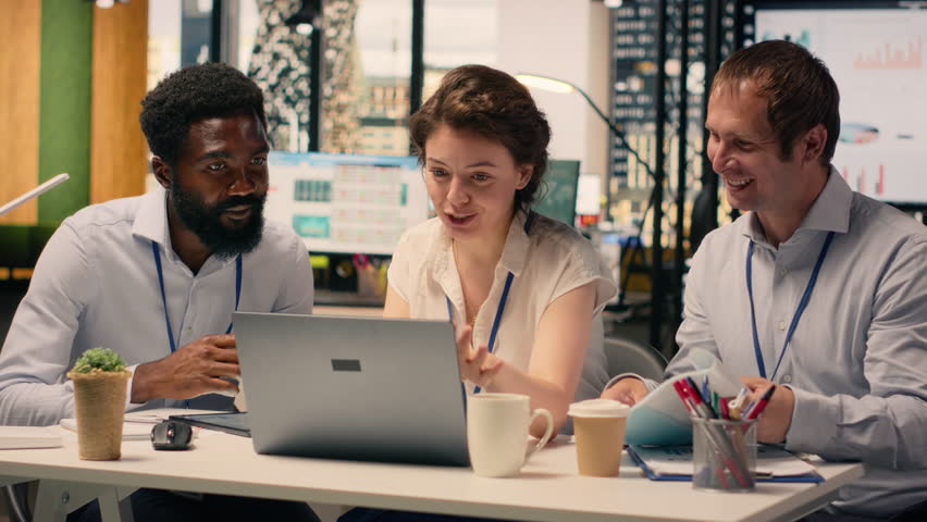 Team collaboration in a corporate office environment with laptop and reports on the table. Professionals reviewing KPI, income data and charts to support planning and decision making.