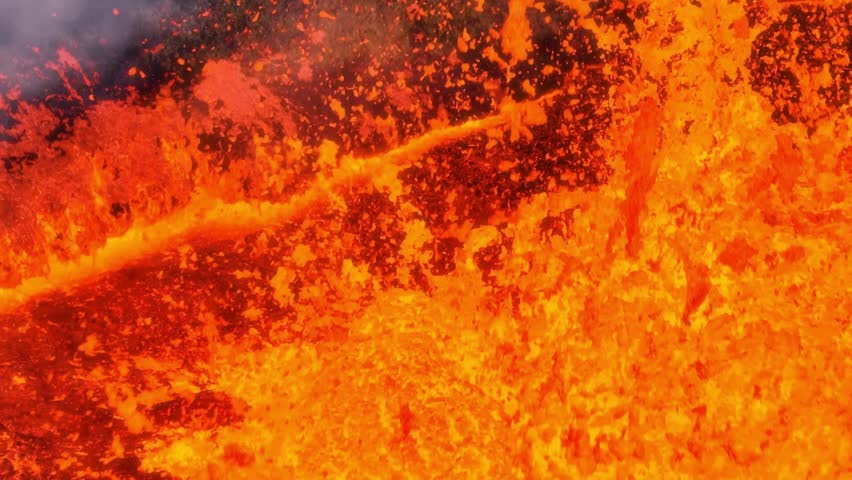 Close up shows a river of molten lava flowing from an erupting volcano in Iceland. Steam rises and cools as the hot lava pours across the landscape, an incredible force of nature.