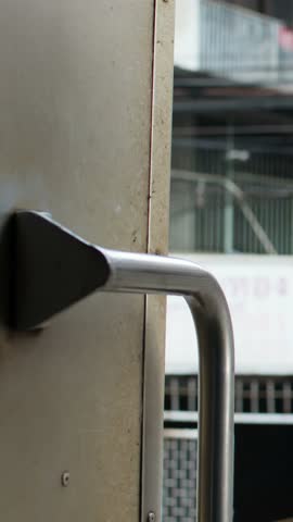 A moving train perspective shows gravel ballast and urban scenery through an open doorway