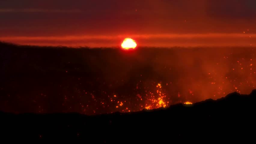 Hot lava is flowing down the side of Kilauea volcano in Hawaii. This abstract background showcases the violent eruption and bright red glow against a dark landscape. Twilight with sunset.