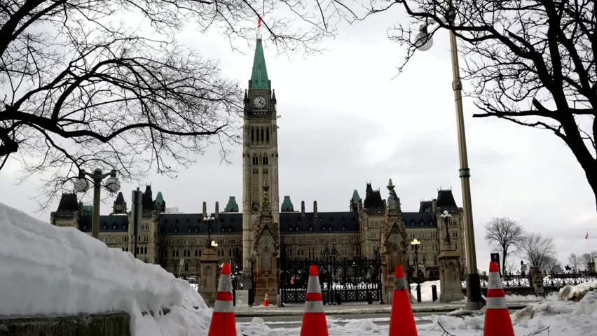 Parliament Building in Ottawa, Canada covered in snow, with traffic cones in winter, highlighting iconic architecture and seasonal urban scene.