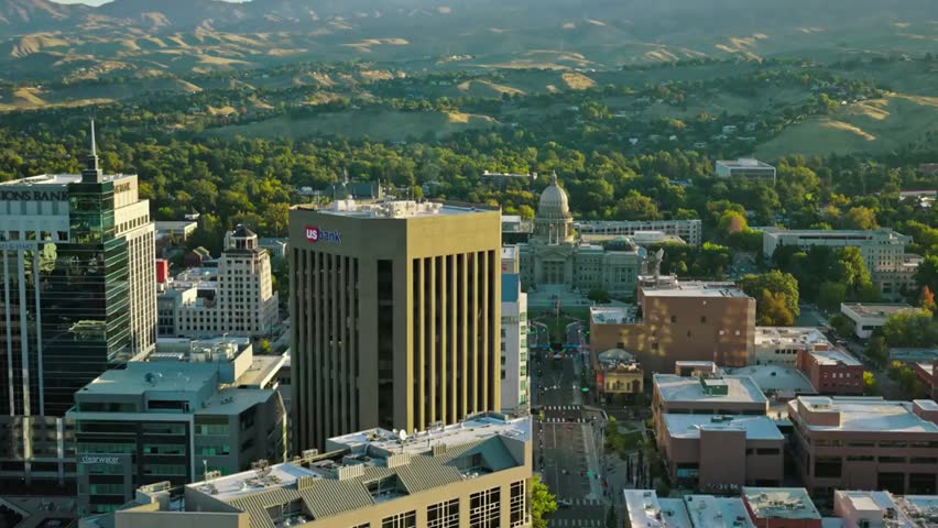 Aerial view of Boise, Idaho skyline with mountains and cityscape in the background, showcasing urban landscape and natural surroundings.