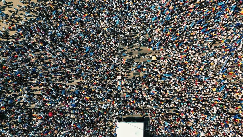 Aerial top down static view of a massive crowd of people moving and gathering for a public event or protest