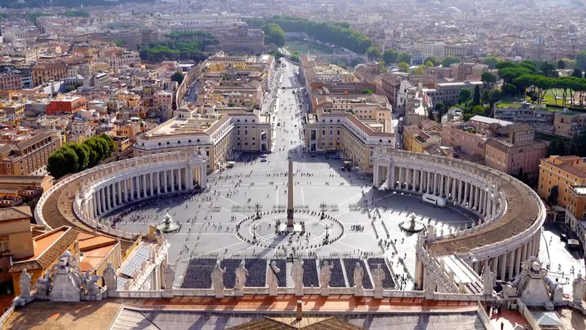 Aerial view of St. Peter’s Square and Vatican City in Rome on a sunny day, showcasing historic architecture and vibrant city life.