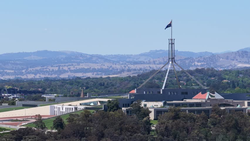 Static wide shot of the Australian Parliament House with the national flag waving atop