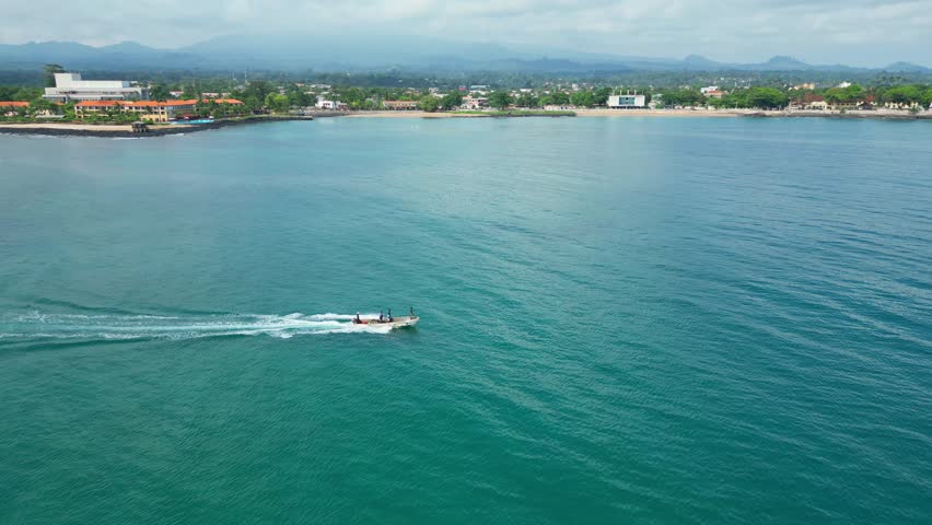 Aerial view of the coast of São Tomé with a fishing boat passing by.Africa