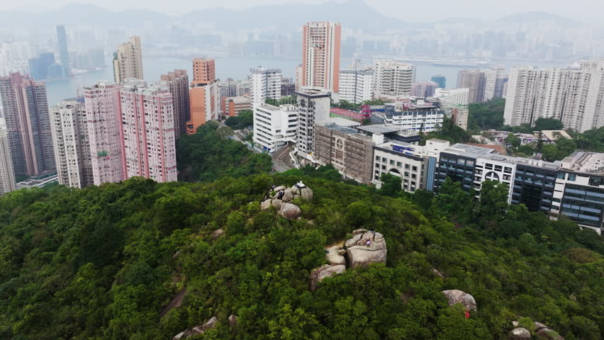 Panoramic drone shot of people at a viewpoint overlooking the city of Hong Kong