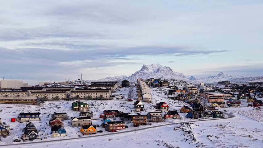 A stunning aerial-style wide shot of Nuuk, Greenland’s capital, showcasing modern architecture and colorful houses nestled beneath the iconic snow-covered Sermitsiaq peak.