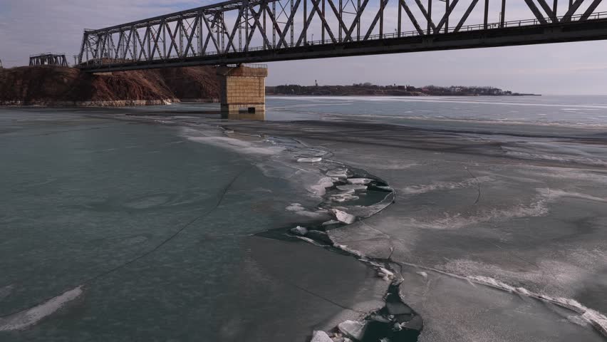 The old iron bridge over the reservoir of ice blocks covering the lake. Winter time. The view from the drone.