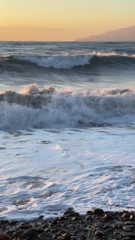 Storm at sea. Waves and shore with stone breakwater, sunny weather in the evening. Sunset season in Liguria. Background for design. 
