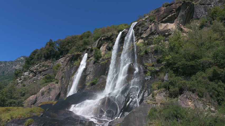 Powerful Acquafraggia waterfalls cascading down rocks in the Italian Alps. Aerial drone lateral view. slow-motion