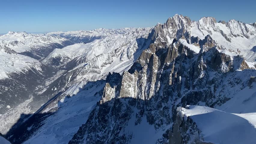 Panoramic sunset view from Mont Blanc showing vast alpine mountain ranges, snowy peaks, dramatic clouds and warm evening light in the European Alps.