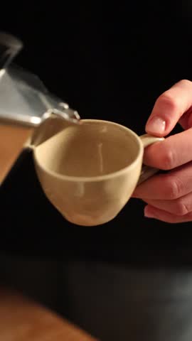 Fresh coffee is poured from a moka pot into a cup in a home kitchen. The video captures a quiet morning routine and the process of brewing a traditional stovetop coffee.