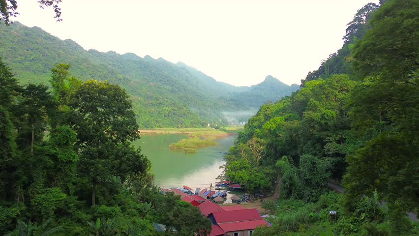 Calm waters of Ba Be Lake reflecting tropical forest and karst mountains in northern Vietnam. Serene natural landscape and travel destination.