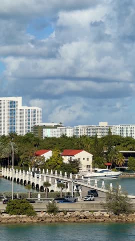 Miami South Beach skyline showcases modern skyscrapers, lush palm trees, and a bustling bridge with vehicles crossing a vibrant blue waterway under a clear sky, representing urban travel and vacation