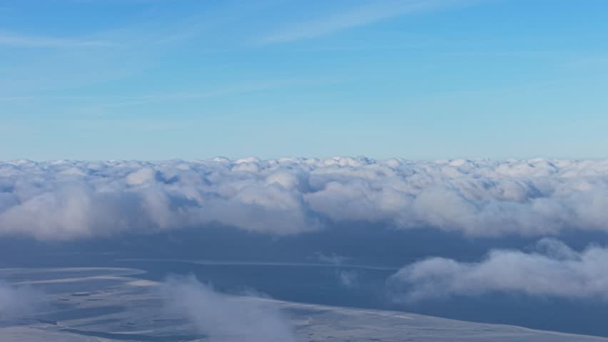 Expansive cloud field under clear blue sky seen from high altitude, soothing peaceful empty background
